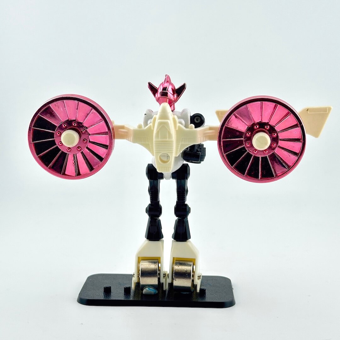 White, black, and pink toy robot with beige accessories on white background. 