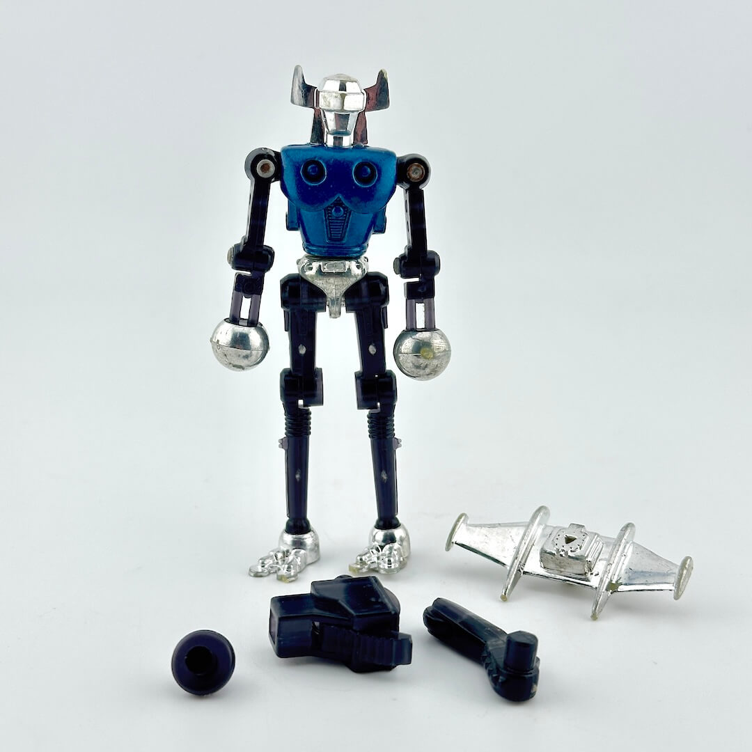 A blue and silver toy robot action figure with several loose accessories arranged in front of it.