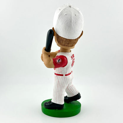 Bobblehead figure of a baseball player in a white and red uniform with a bat on a green base against a light gray background.