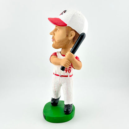 Bobblehead of a baseball player in a red and white uniform with a bat on a green base against a white background