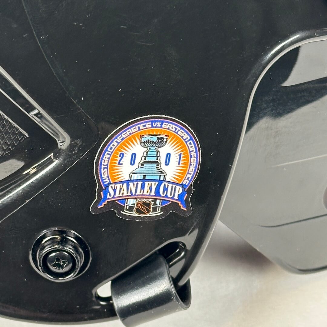 Close-up of a hockey helmet with a Stanley Cup logo on a black background