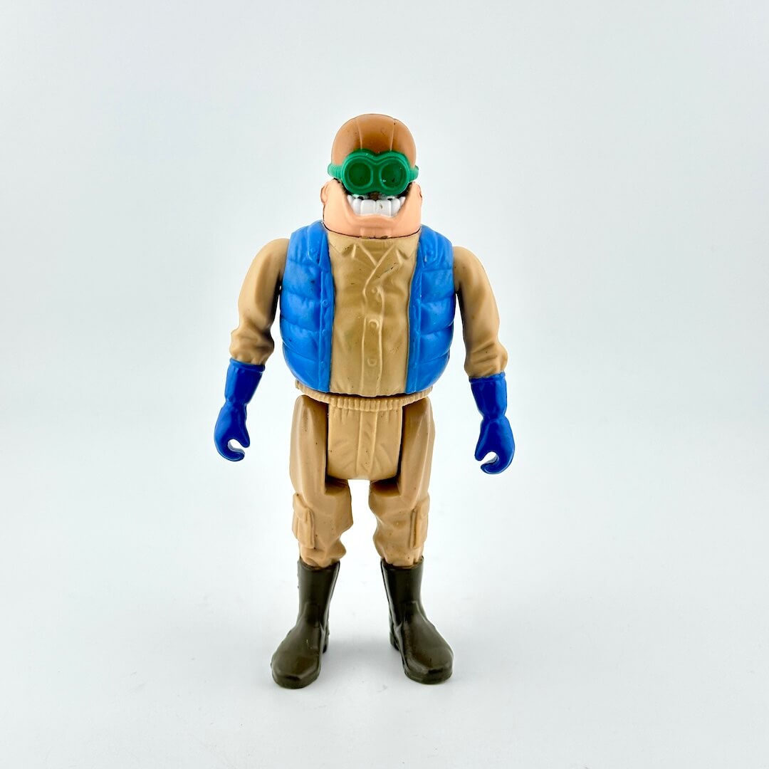 Action figure with a blue vest and green goggles on a white background