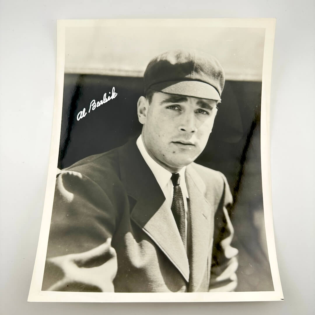 Vintage black and white photo of a man wearing a suit and tie with a signature above his head.