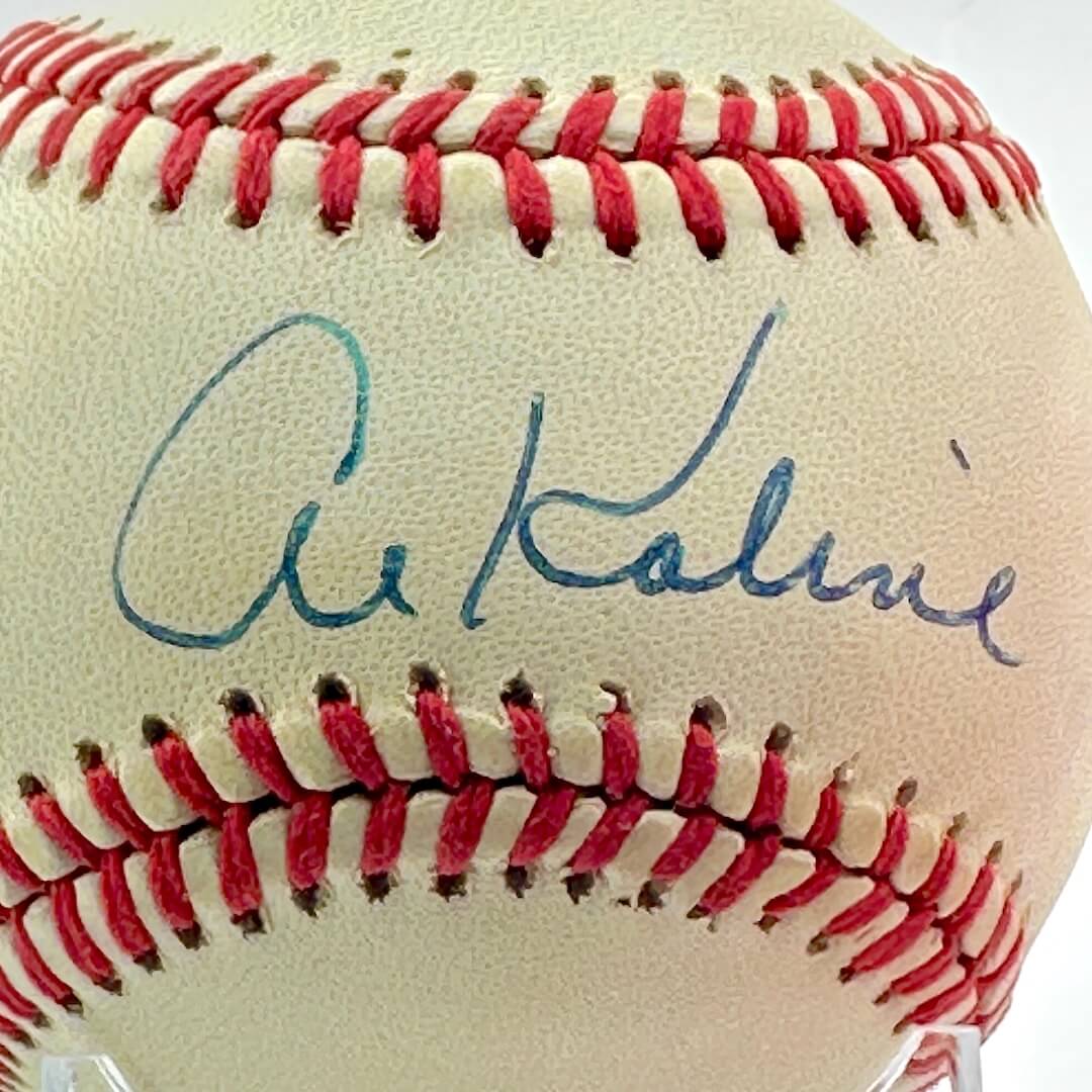 Signed baseball in clear display against white background. Close up of signature in blue pen. 