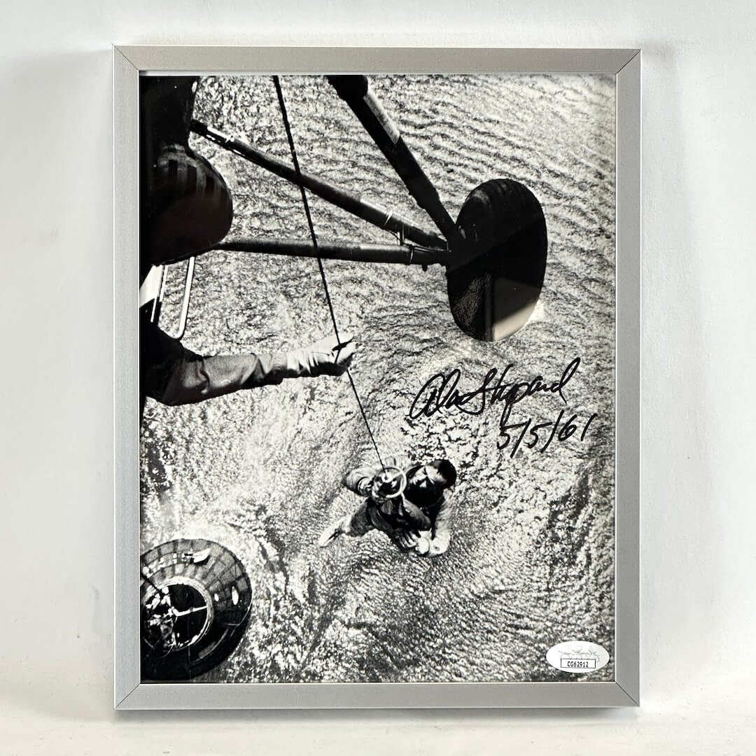 Framed black and white photo of water recovery of Alan Shepard from landing craft. Signed in black marker. Authentication sticker in corner. 