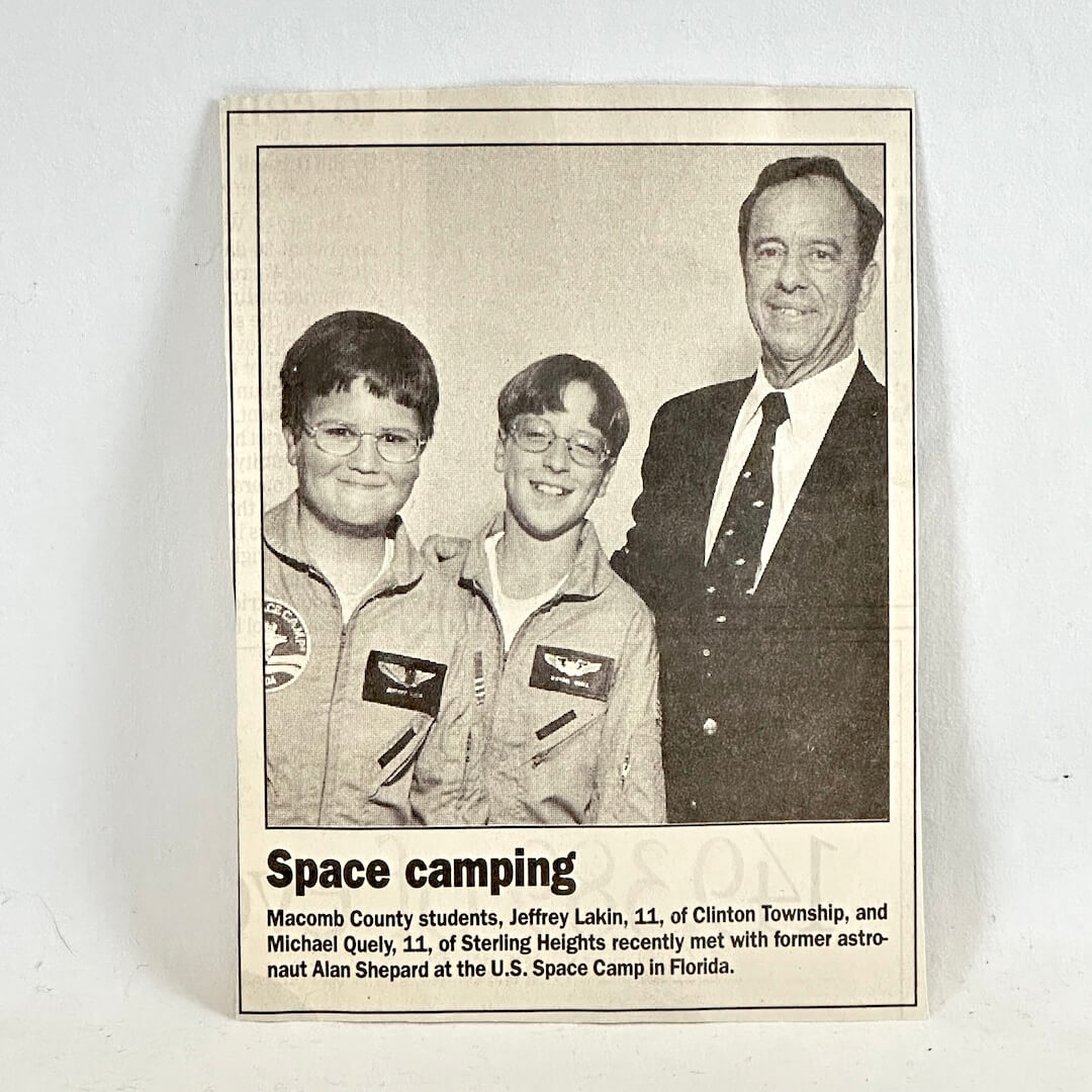 Newspaper clippning with two kids and man smiling at camera with caption below. 