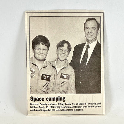 Newspaper clippning with two kids and man smiling at camera with caption below. 