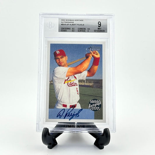 Autographed baseball card in clear plastic capsule on black easel against white background. 