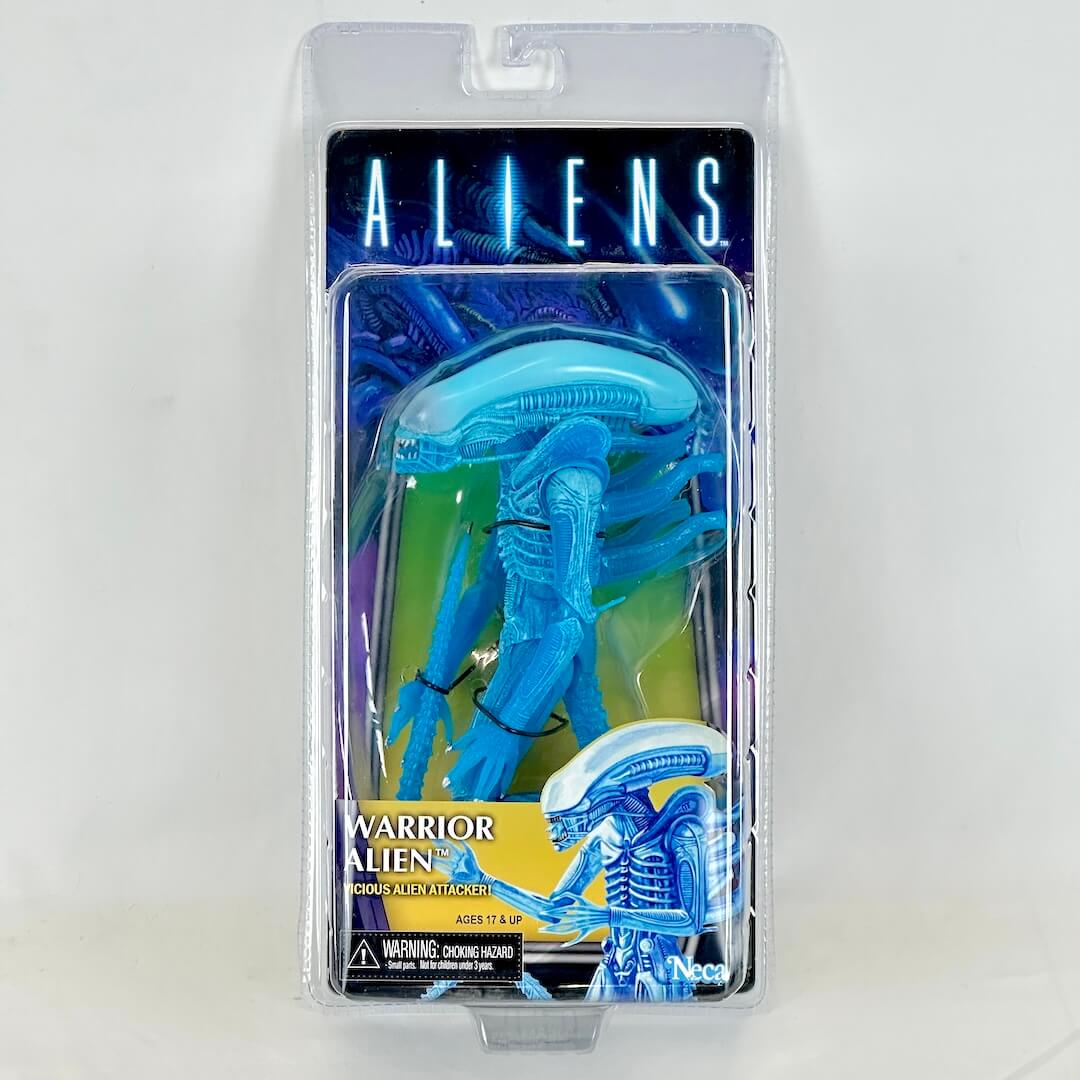 Toy figure of an alien warrior in packaging with 'Aliens' branding on a white background