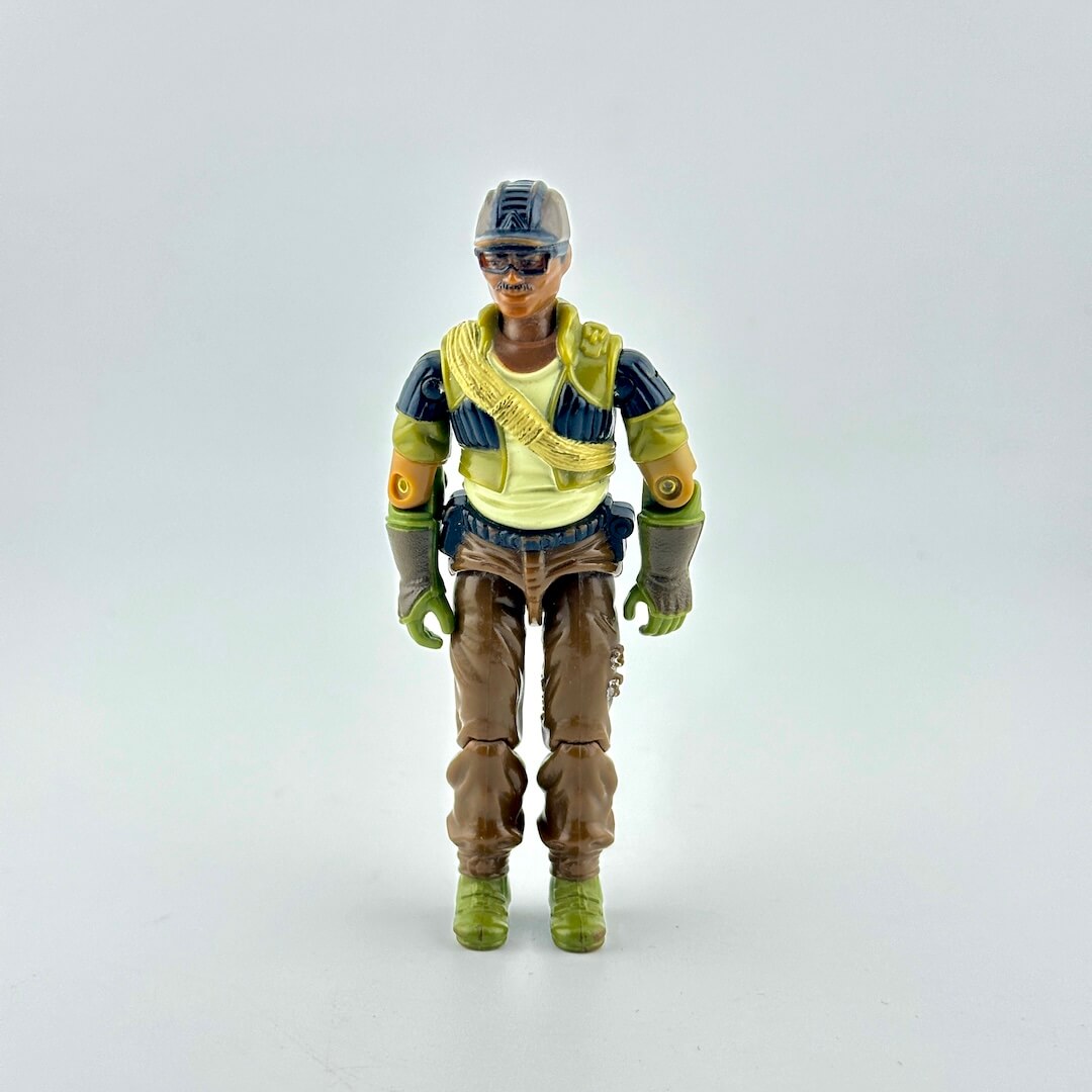 A vintage action figure of a soldier wearing a brown hat, black and green tactical vest, brown pants, and green boots.