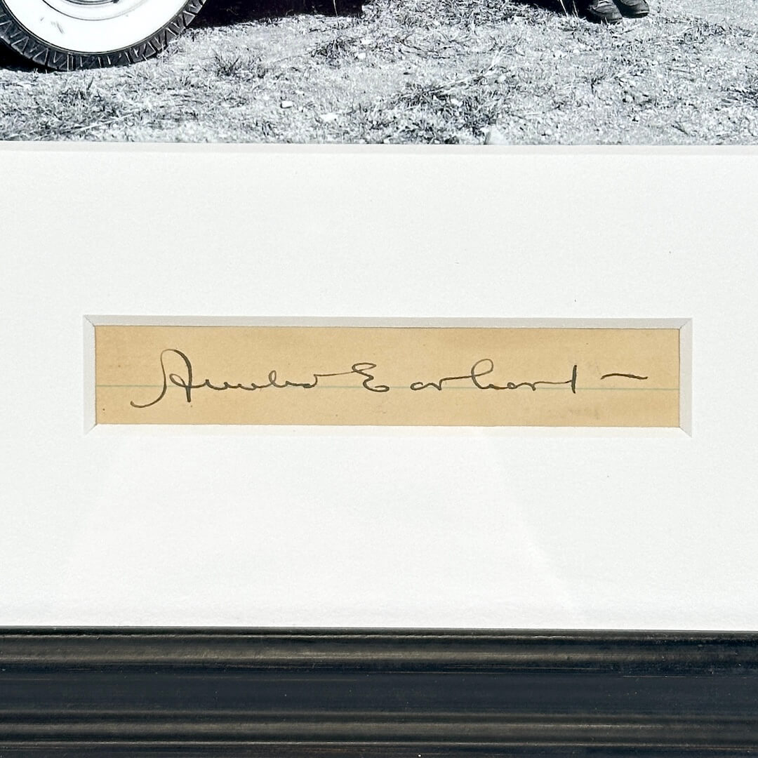 Close-up of a signature on a white background with a tire at the top.