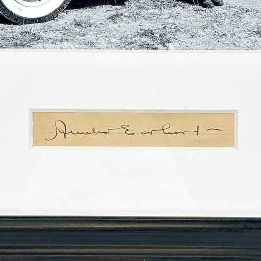 Close-up of a signature on a white background with a tire at the top.