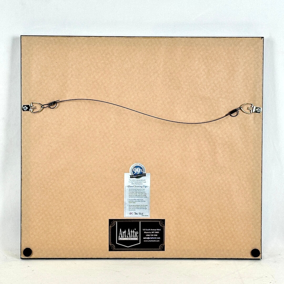 Back of a framed artwork with Art Attic branding and glass cleaning tape label.