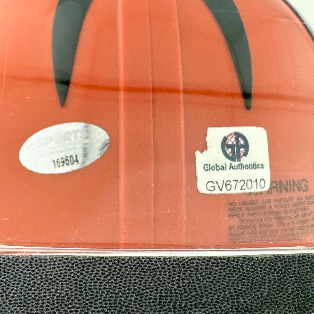 Close-up of authentication stickers on back of orange helmet. 