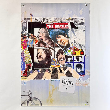 Poster collage of The Beatles' images on a textured surface with a bicycle at the bottom.