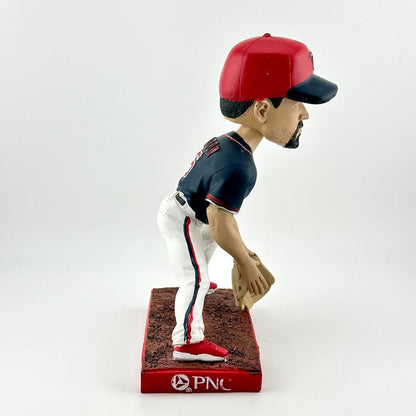 Baseball bobblehead figure with red and blue cap, navy jersey, and white pants on a white background.