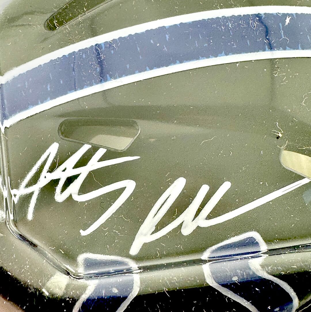 Close-up of a signature on a black surface with blue and white stripes.