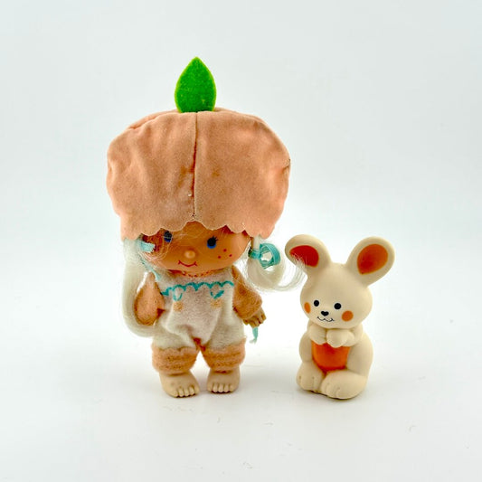 Toy baby doll with peach outfit and white bunny toy. 