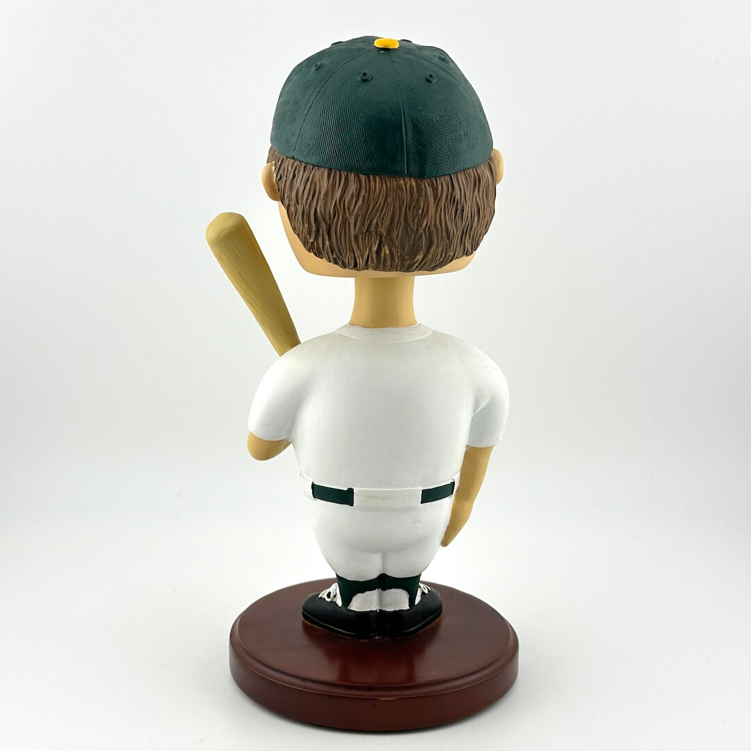 Bobblehead figure of a baseball player with a green cap and white uniform on a white background