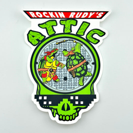 Decorative sticker with TMNT stylized Grateful Dead terrapin turtles and 'Rockin Rudy's Attic' text on a light gray background.