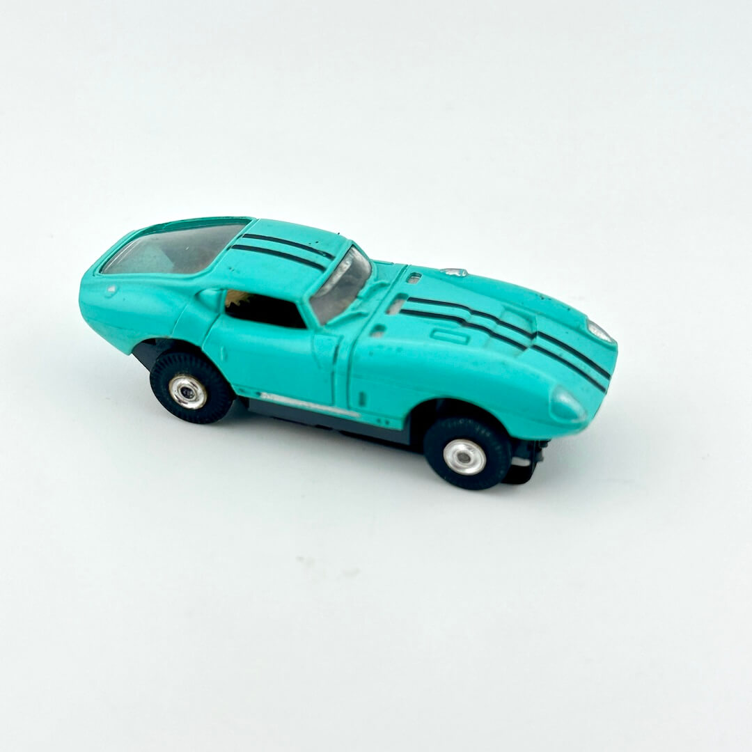 Turquoise toy car with black stripes on a white background