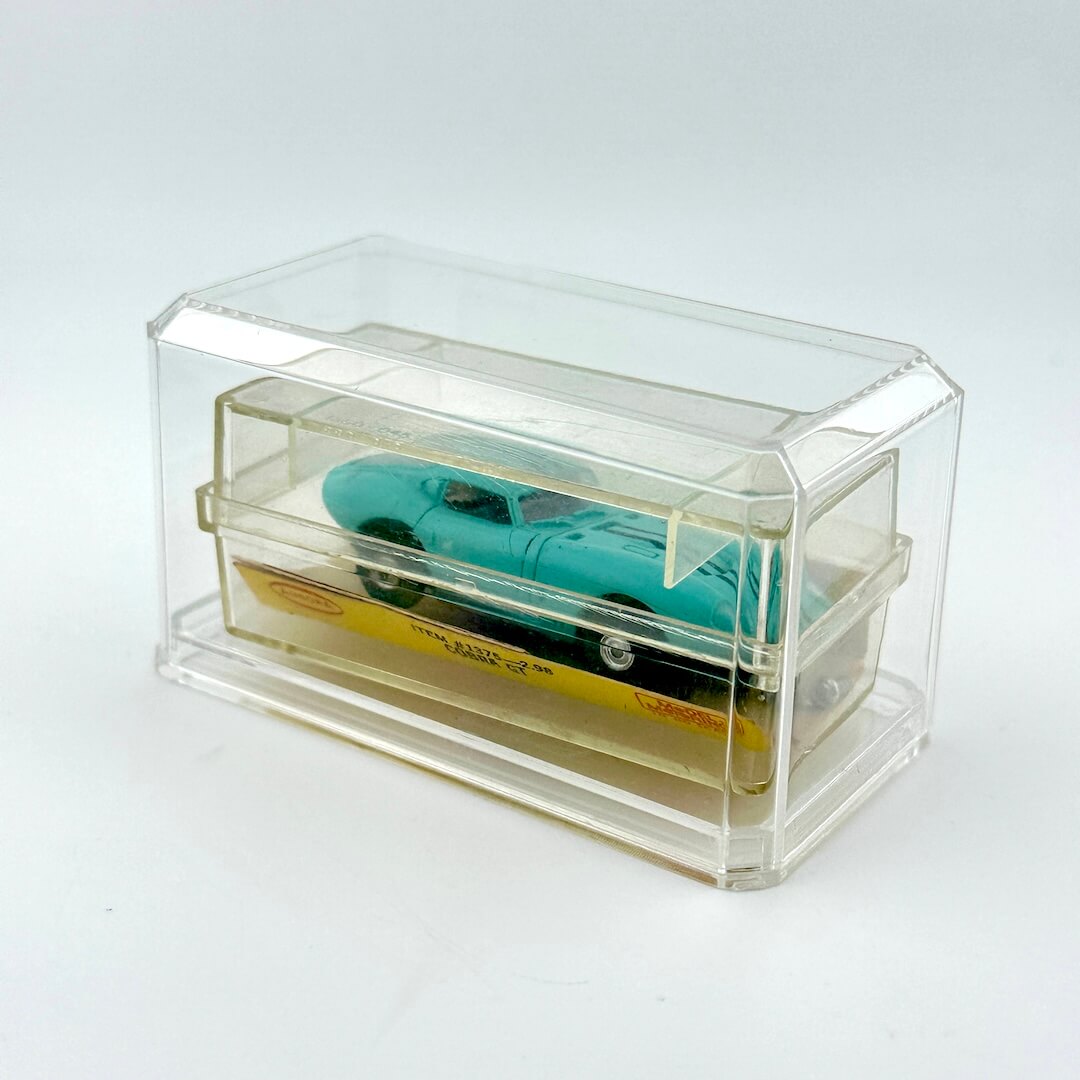 Turquoise model car inside a clear display case on a white background