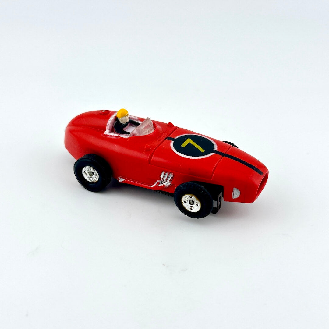 Red slot car with driver against white background.