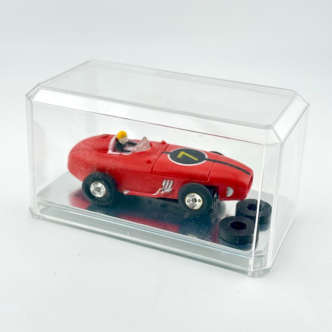 Red model car with a driver figure inside a clear display case on a white background