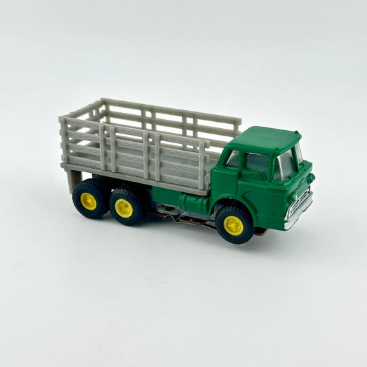 Model truck with green cab and gray bed on a white background