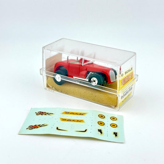 Model car in a clear display case with a set of decals on a white background