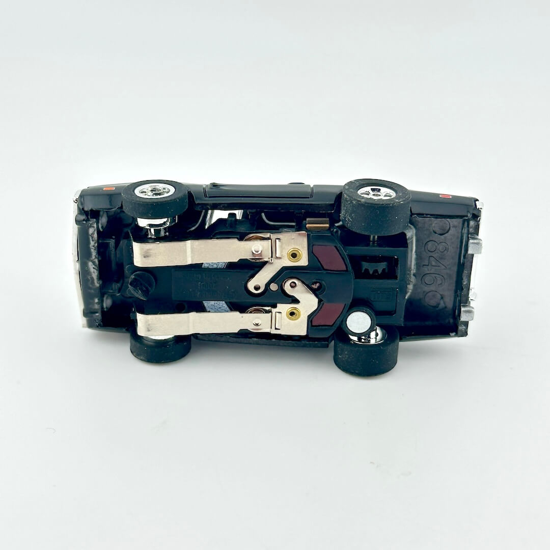 Underside of slot car to show components on white background.