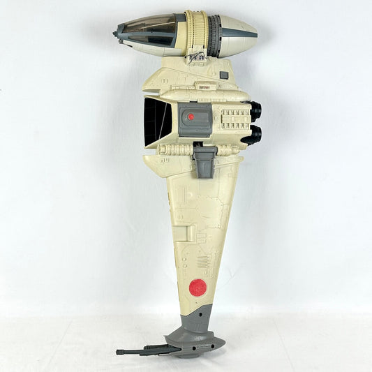A Star Wars toy model, specifically a B-Wing Fighter, in a desert tan and gray color scheme with a red insignia.