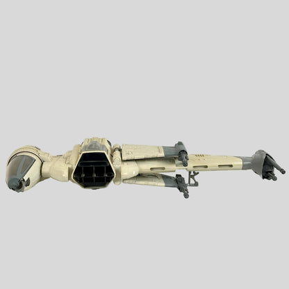 A vintage Star Wars B-wing fighter toy spacecraft, shown from a side profile view on a white fabric surface against a light gray background.