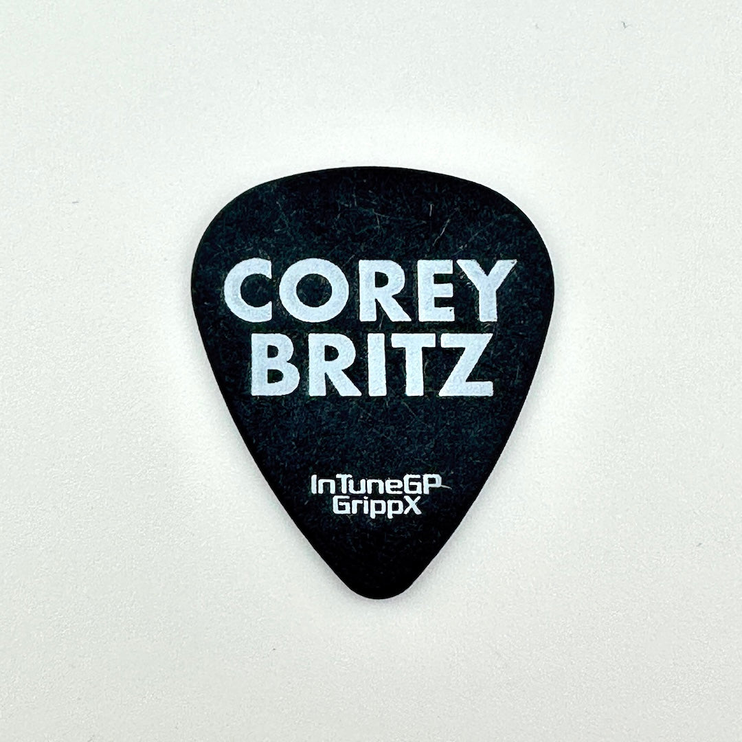 A black guitar pick with white text reading 'COREY BRITZ' and 'InTune6P GrippX' on a plain light background.