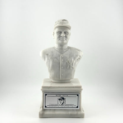 Marble pedestal with marble bust of Babe Ruth in Yankees uniform. Silver plaque on pedestal.