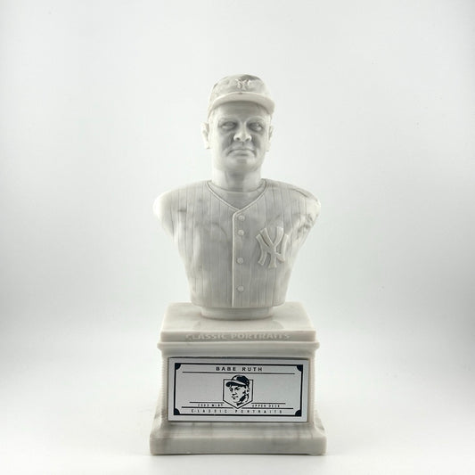 Marble pedestal with marble bust of Babe Ruth in Yankees uniform. Silver plaque on pedestal.