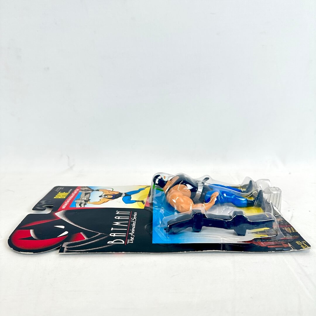 Toy figure of a superhero on a Batman-themed packaging against a white background