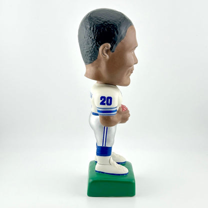 Bobblehead figure of a sports player in a white uniform with blue accents on a white background