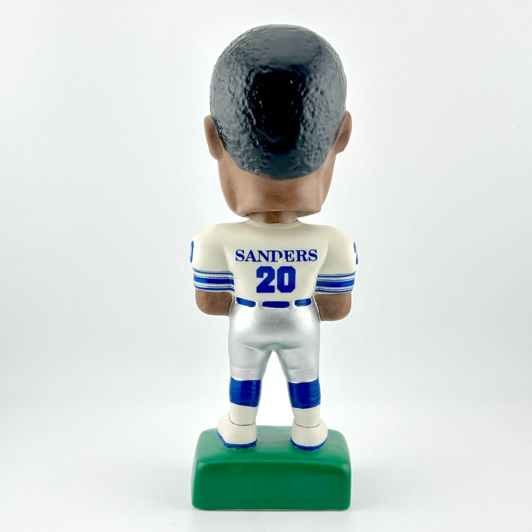 Bobblehead figure of a sports player in a white uniform with blue accents on a white background