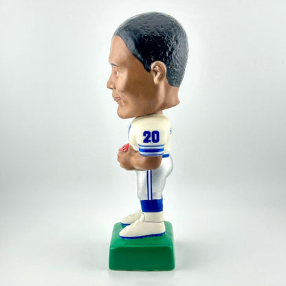 Bobblehead figure of a sports player in a white uniform with blue accents on a green base.