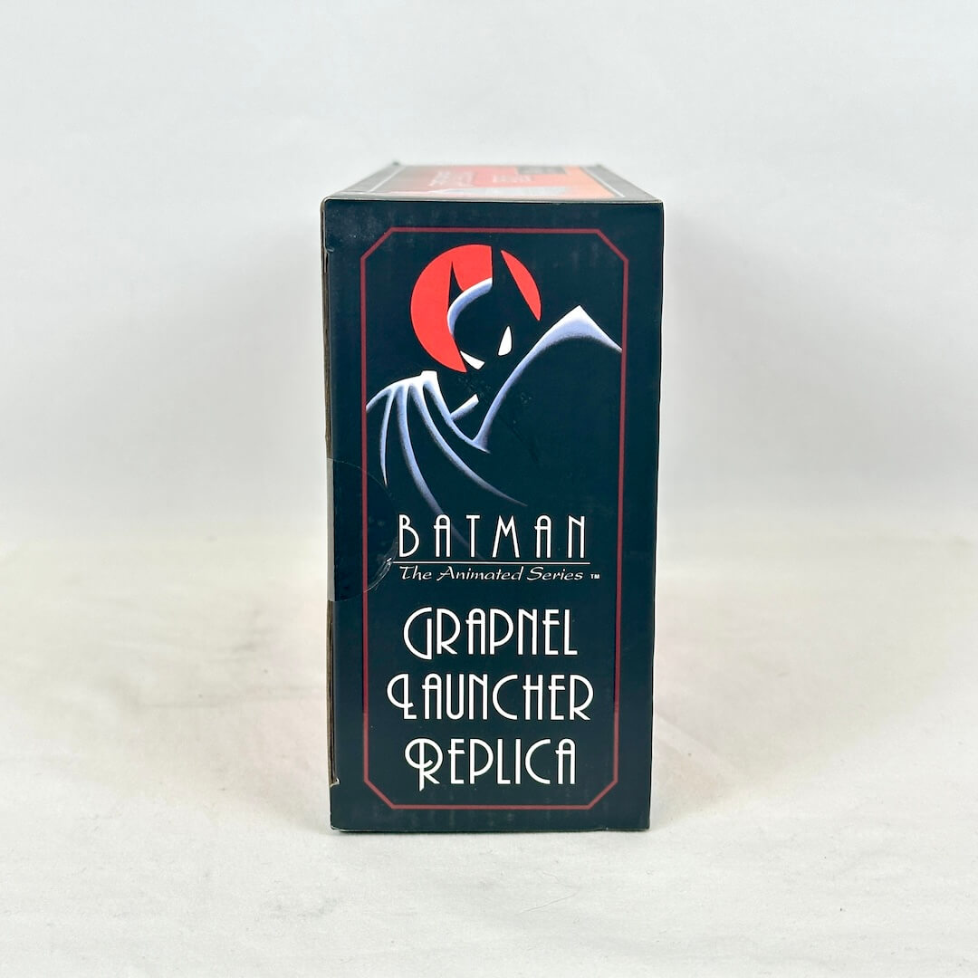 A boxed replica product standing upright on a light neutral surface. 