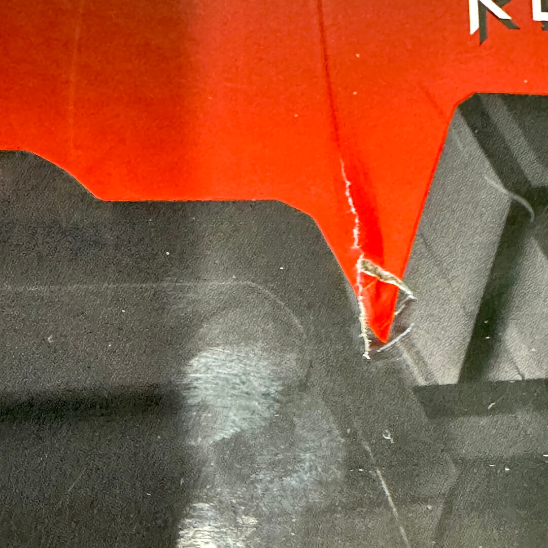 Close-up of a red and black product surface with a torn edge showing white fibers.