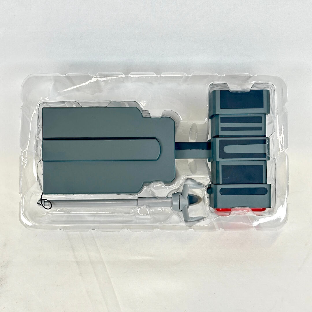 Gray plastic toy set into clear packaging photographed on neutral background. 
