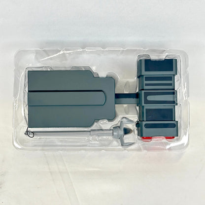 Gray plastic toy set into clear packaging photographed on neutral background. 