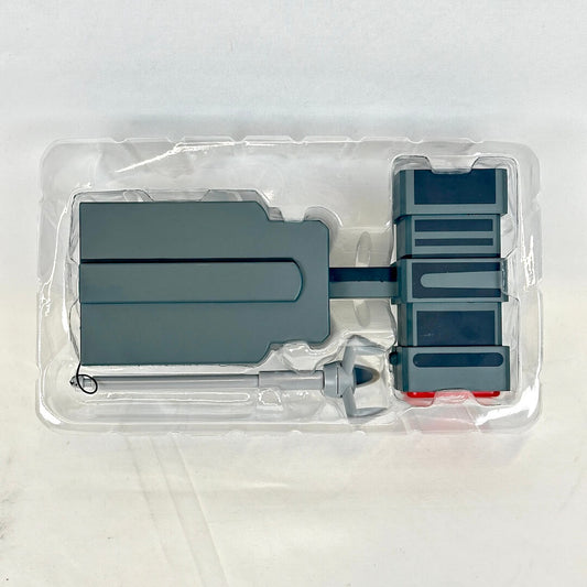 Gray plastic toy set into clear packaging photographed on neutral background. 