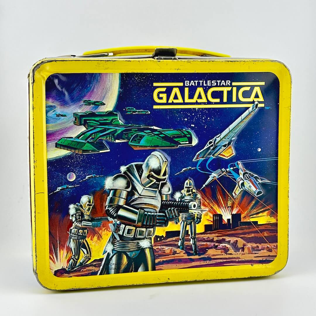Vintage metal lunchbox with yellow border and sci-fi imagery with robots and flying ships against starry sky. 