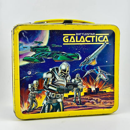 Vintage metal lunchbox with yellow border and sci-fi imagery with robots and flying ships against starry sky. 