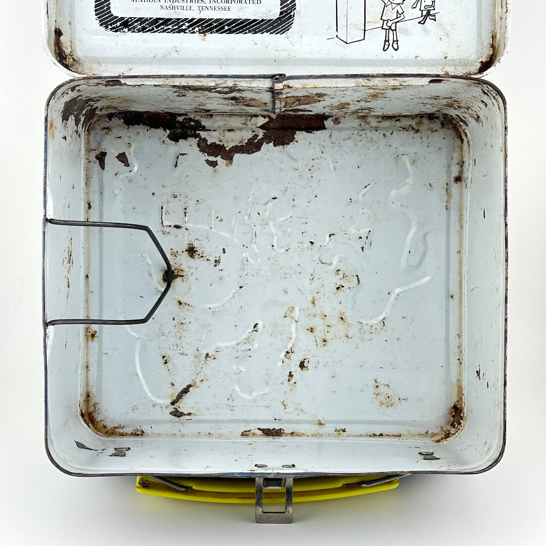 View of interior of vintage metal lunchbox with rust spots and clip for thermos. 
