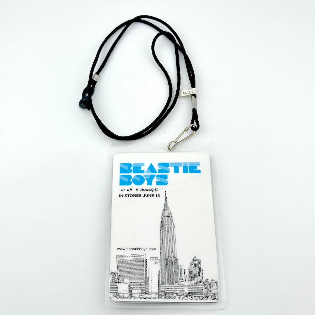 Lanyard with a Beastie Boys-themed badge featuring a cityscape illustration on a white background.