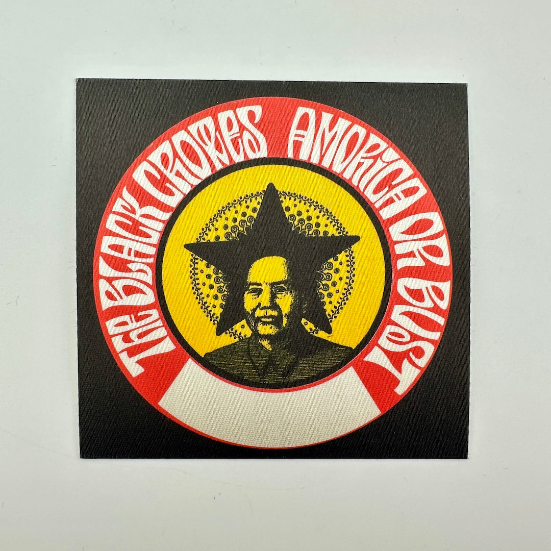 A square black patch featuring a circular graphic with red outer ring, white text, a yellow center, and a portrait of Mao Zedong inside a star.